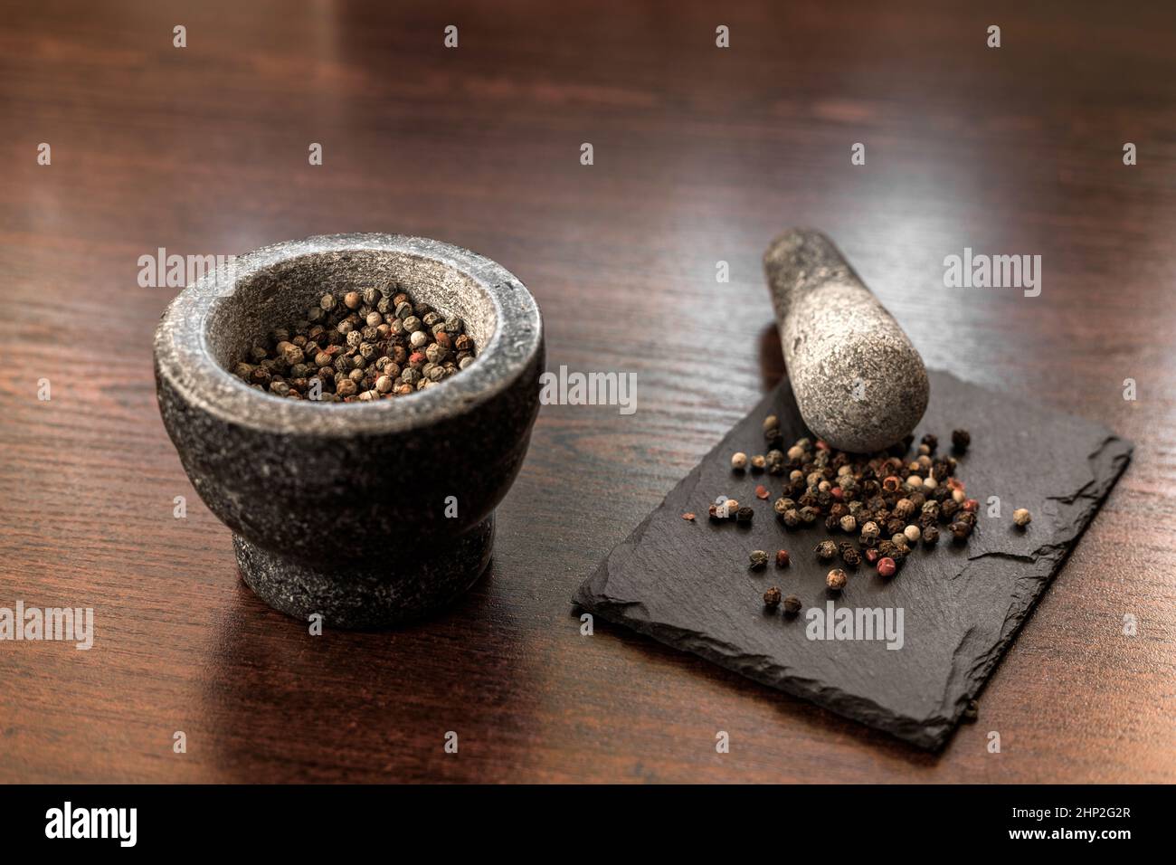 Pfefferkörner aus schwarzem und farbigem Pfeffer mit Granitmörtel Stockfoto