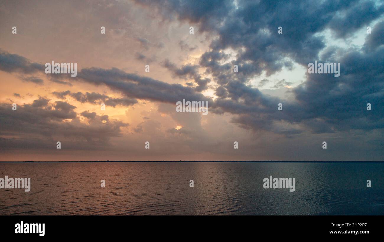 Wunderschöne Landschaft des Sonnenuntergangs am Strand. Ruhiges Wetter mit blauen Wolken am blauen Himmel, die sich im Wasser spiegeln. Stockfoto