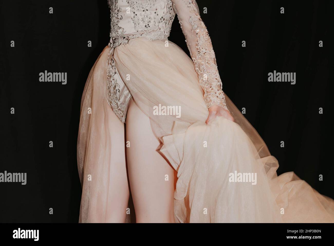 Weibliche Figur in einem üppigen Abendkleid in Beige auf schwarzem Hintergrund Stockfoto