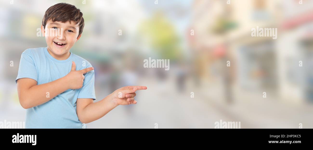 Kind Kind kleiner Junge, der mit dem Finger auf Werbung in der Stadt zeigt, mit Copyspace-Kopierraum latein Stockfoto