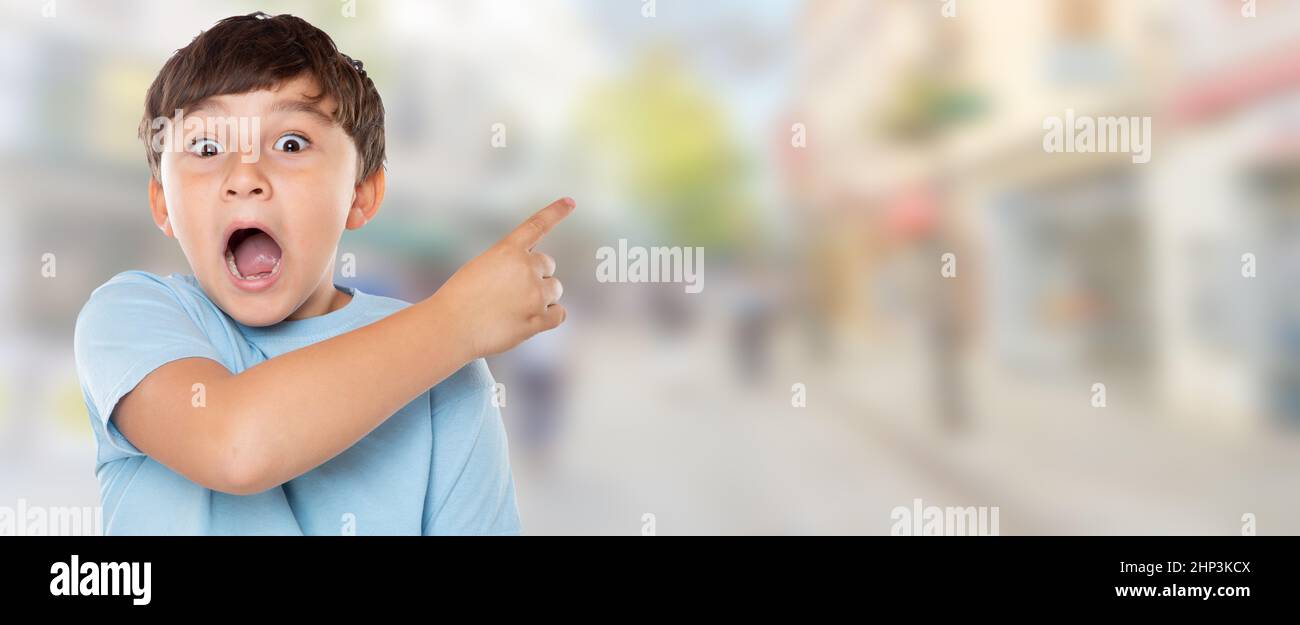 Kind Kind überrascht überrascht kleinen Jungen zeigt auf Werbung in der Stadt mit Copyspace Kopie Raum Stadt Stockfoto