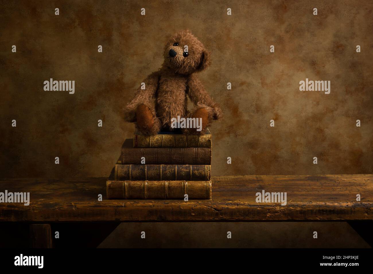 Niedlicher brauner Teddybär und gestapelte Bücher auf einem rustikalen alten Holzregal. Dies ist für digitales Compositing geeignet. Stockfoto