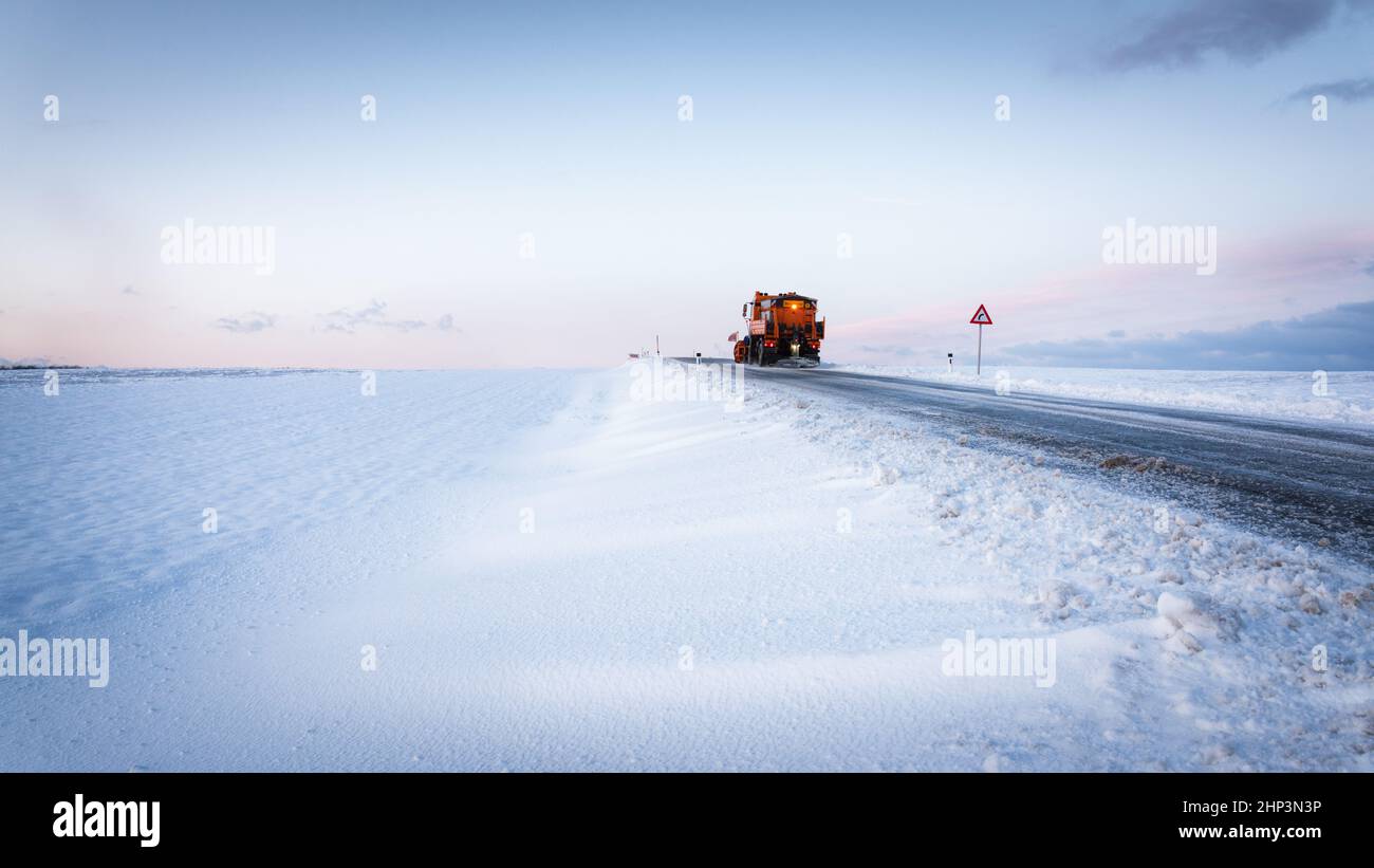 Schneepflug auf der Autobahn Salzstraße . Orange Truck Deicing Street. Wartung Winter Fahrzeug breites Panorama oder Banner. Stockfoto