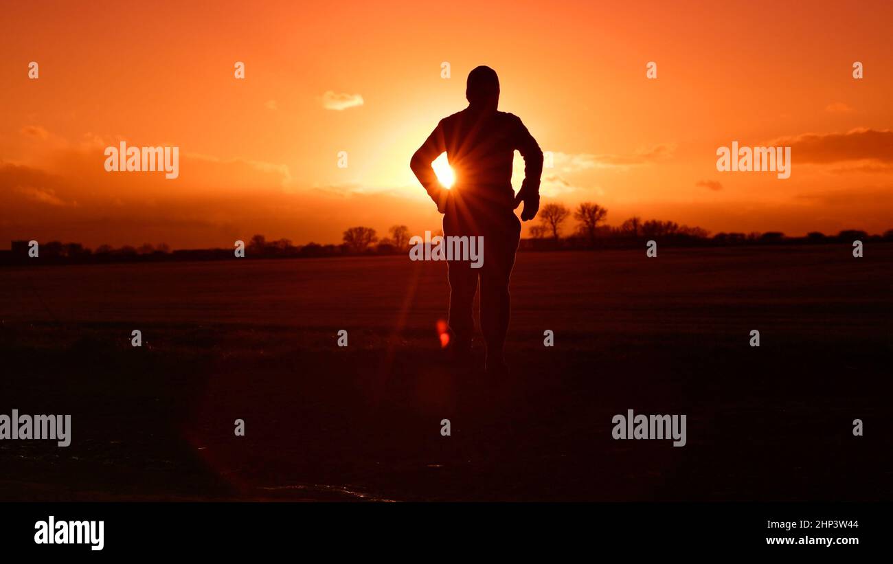 Person, die bei Sonnenuntergang auf dem Land läuft Stockfoto