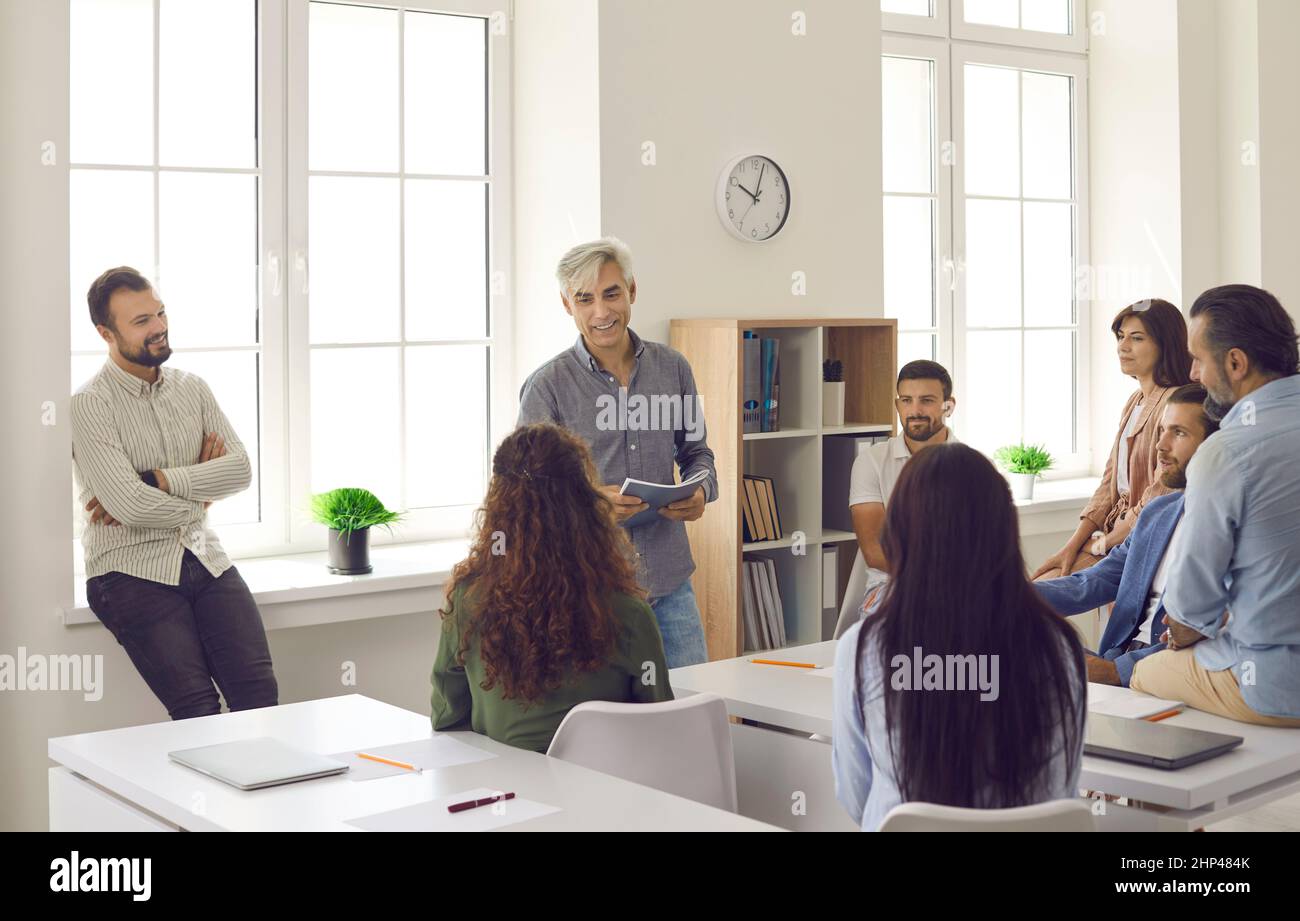 Team von Mitarbeitern, die während des Schulungsmeeting im Büro dem Senior Business Coach zuhören Stockfoto