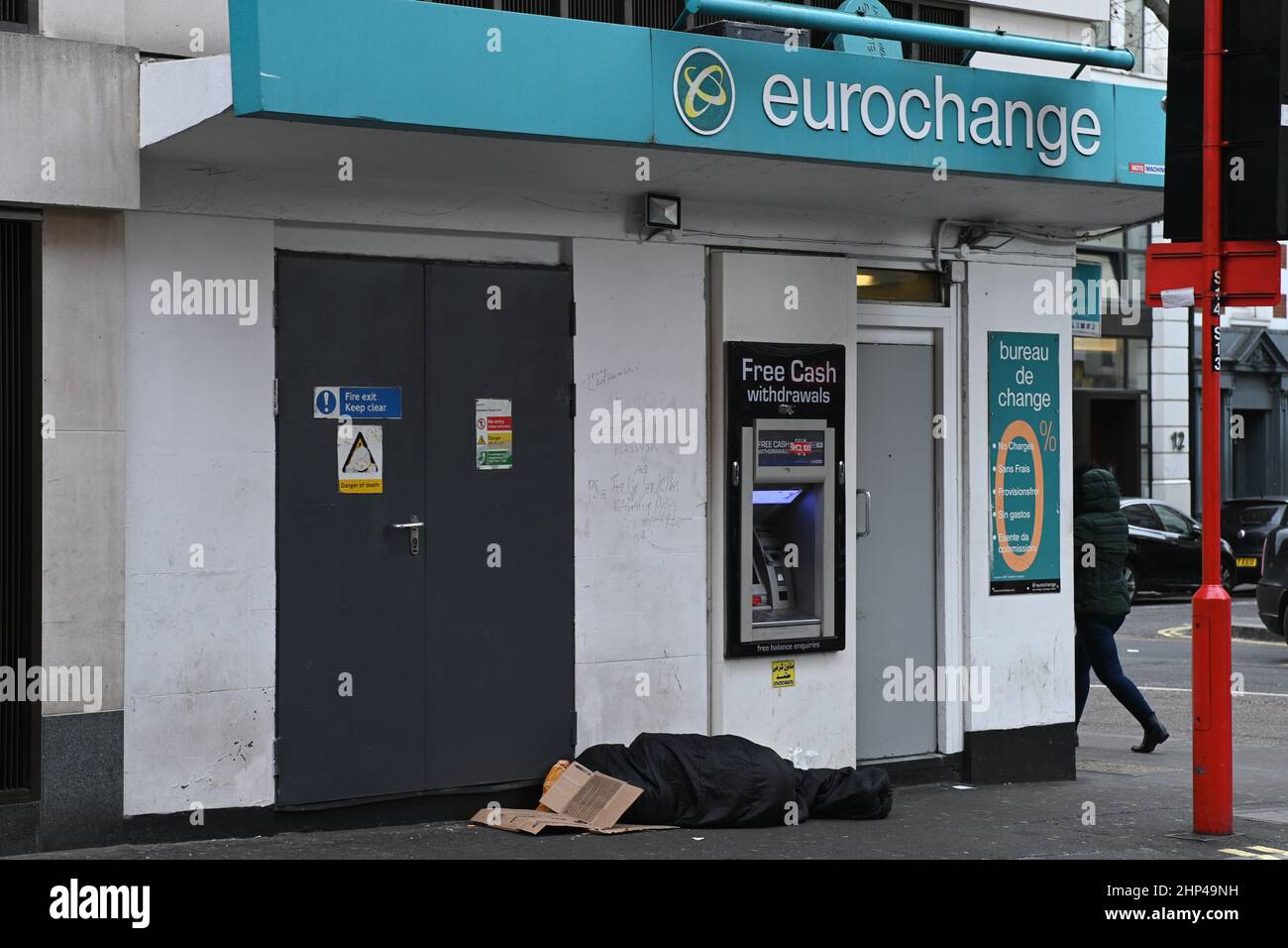 London, Großbritannien. 18th. Februar 2022. Wetter in London, Großbritannien, 18. Februar 2022. Eine Obdachlose schläft vor dem Eurochange-Geldautomat am Leicester Square. Kredit: Picture Capital/Alamy Live Nachrichten Stockfoto