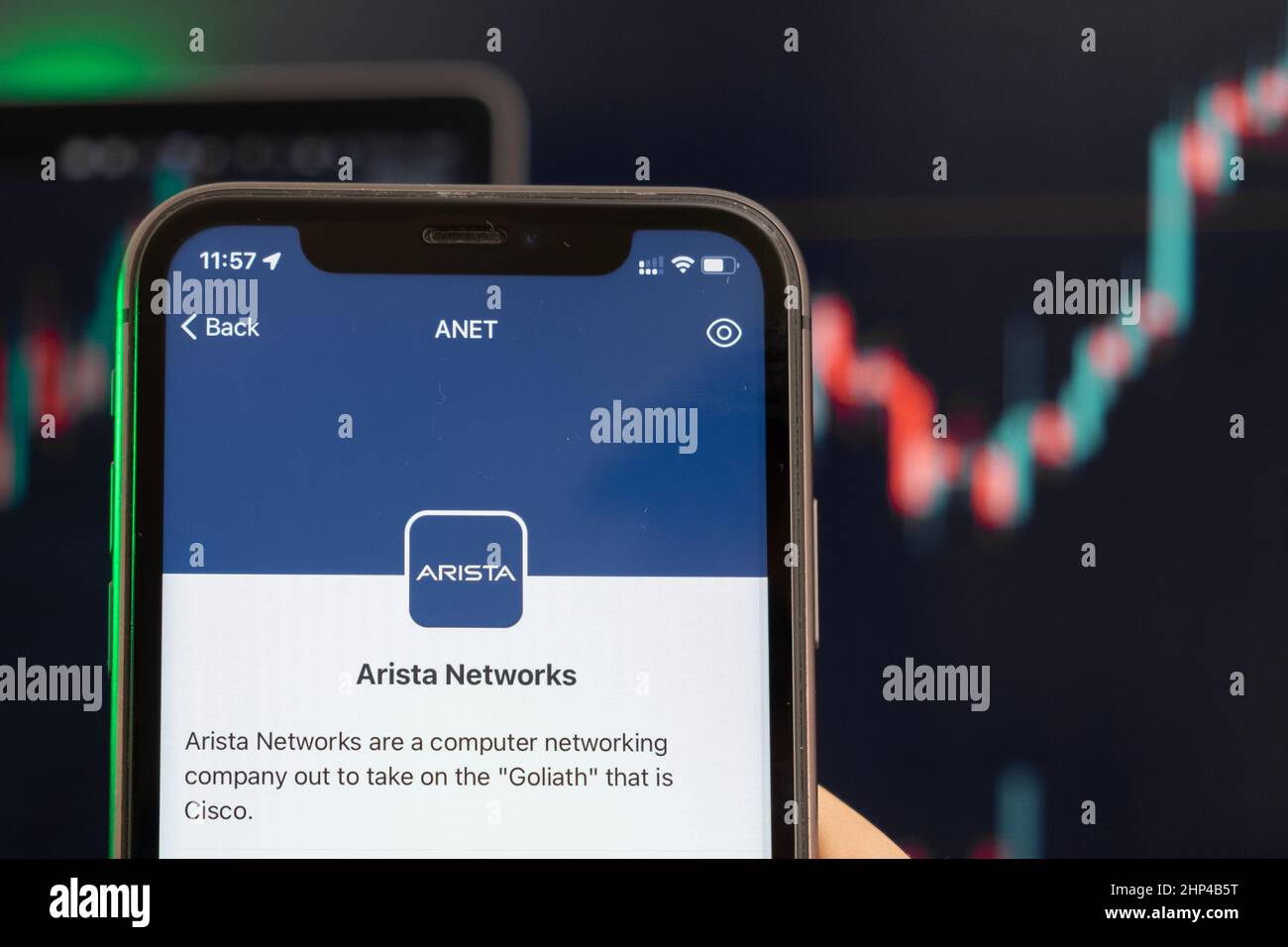 Der Aktienkurs von Arista Networks steigt am Handelsmarkt mit einem Balkendiagramm mit Aufwärtstrend-Linien im Hintergrund. Mann mit Mobiltelefon und Firmenlogo, Februar 2022, San Francisco, USA Stockfoto