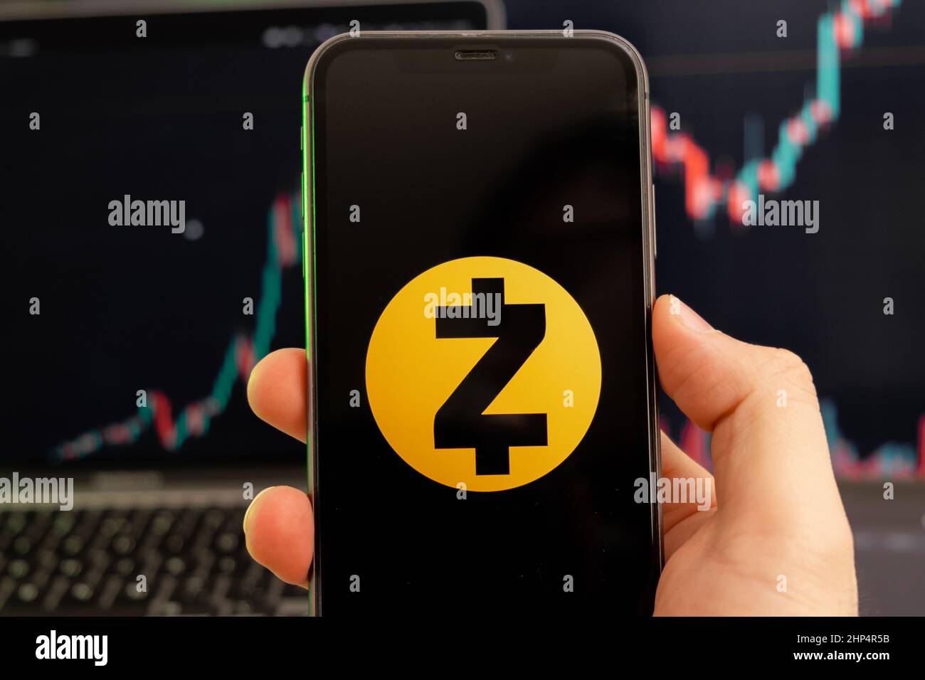 Zcash ZEC Kryptowährung Logo auf dem Bildschirm eines Smartphones in mans Hand mit einem wachsenden Trend auf dem Chart auf grünem Hintergrund. Stockfoto