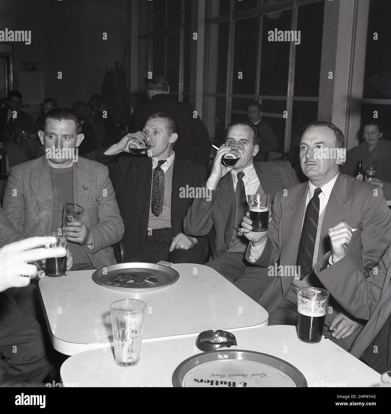 1950s, historisch, im Sozialclub der Fabrik, eine Gruppe von Stahlarbeitern, die nach ihrer Schicht an einem kleinen Tisch saßen und ein Pint Bier genossen, Port Talbot, Wales, Großbritannien. Stockfoto