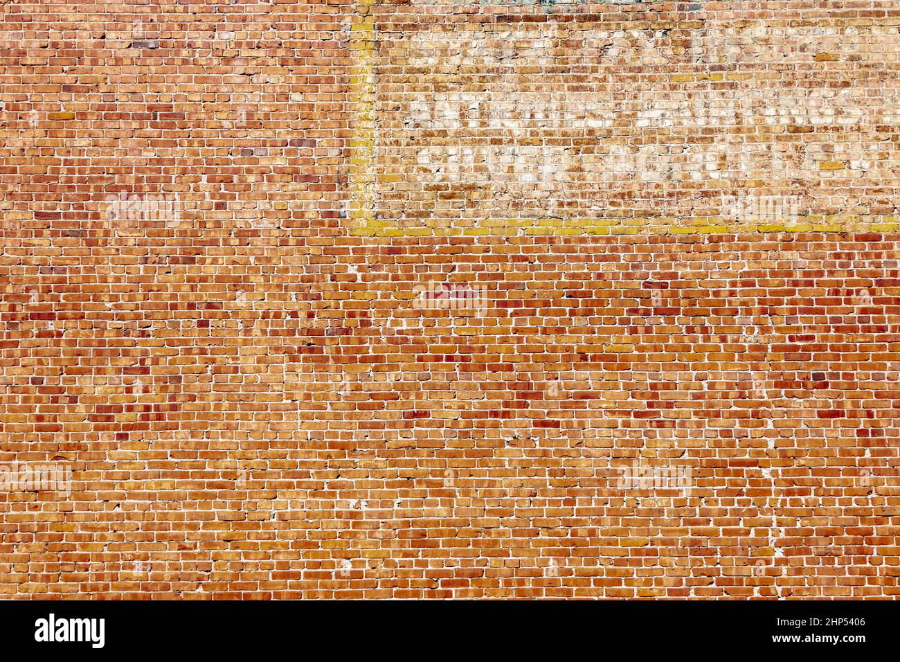 Rote Backsteinmauer aus dem 19th. Jahrhundert mit verblassten, bemalten Schilder. Stockfoto