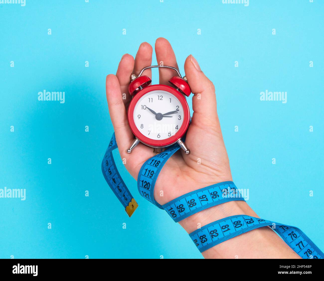 Wecker rote Farbe in Frau Hand auf hellblauem Hintergrund Stockfoto