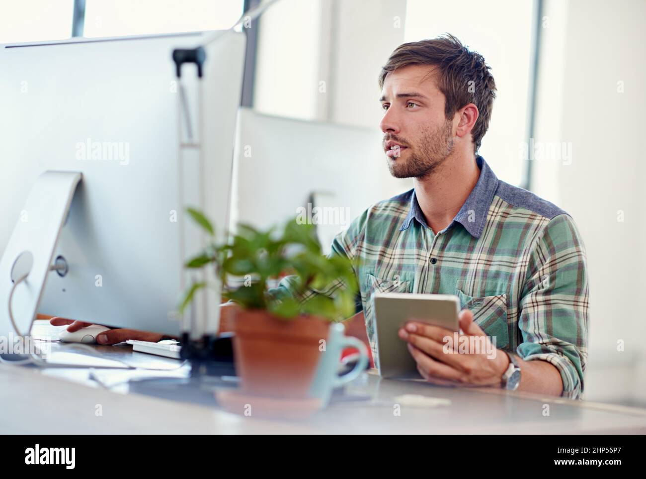Fortschrittliches Design. Aufnahme eines lässig gekleideten jungen Mannes, der ein digitales Tablet an seinem Schreibtisch verwendet. Stockfoto