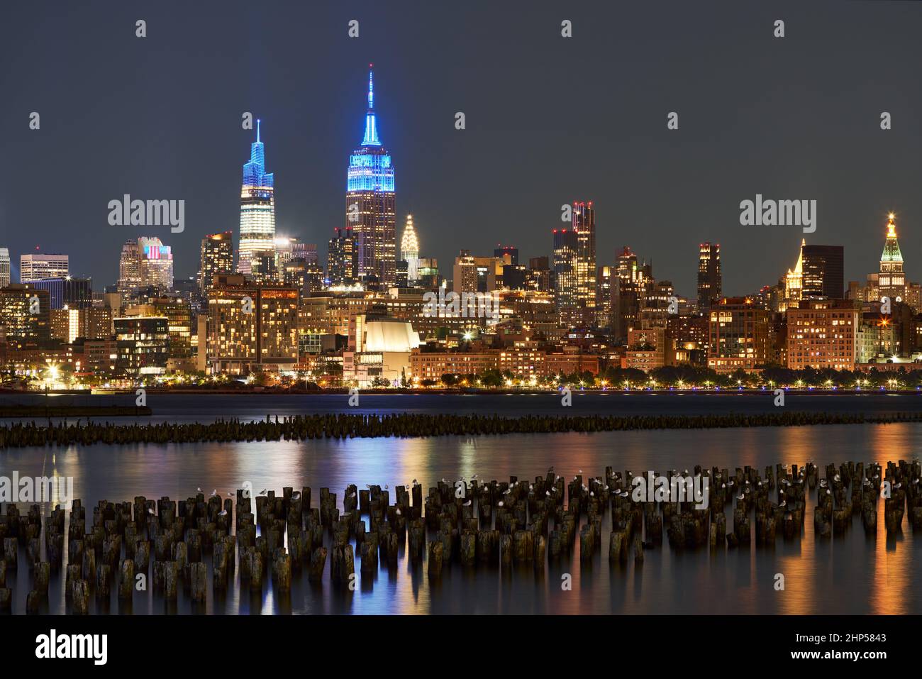 Historische Wolkenkratzer von New York, die nachts über den Hudson River beleuchtet werden. Stadtbild von West Village und Midtown Manhattan Stockfoto