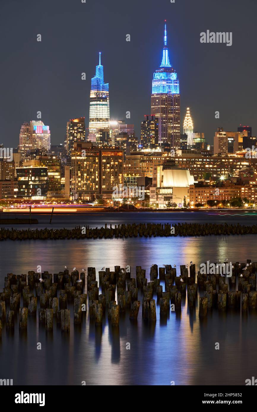 Historische Wolkenkratzer von New York, die nachts über den Hudson River beleuchtet werden. Stadtbild von West Village und Midtown Manhattan Stockfoto