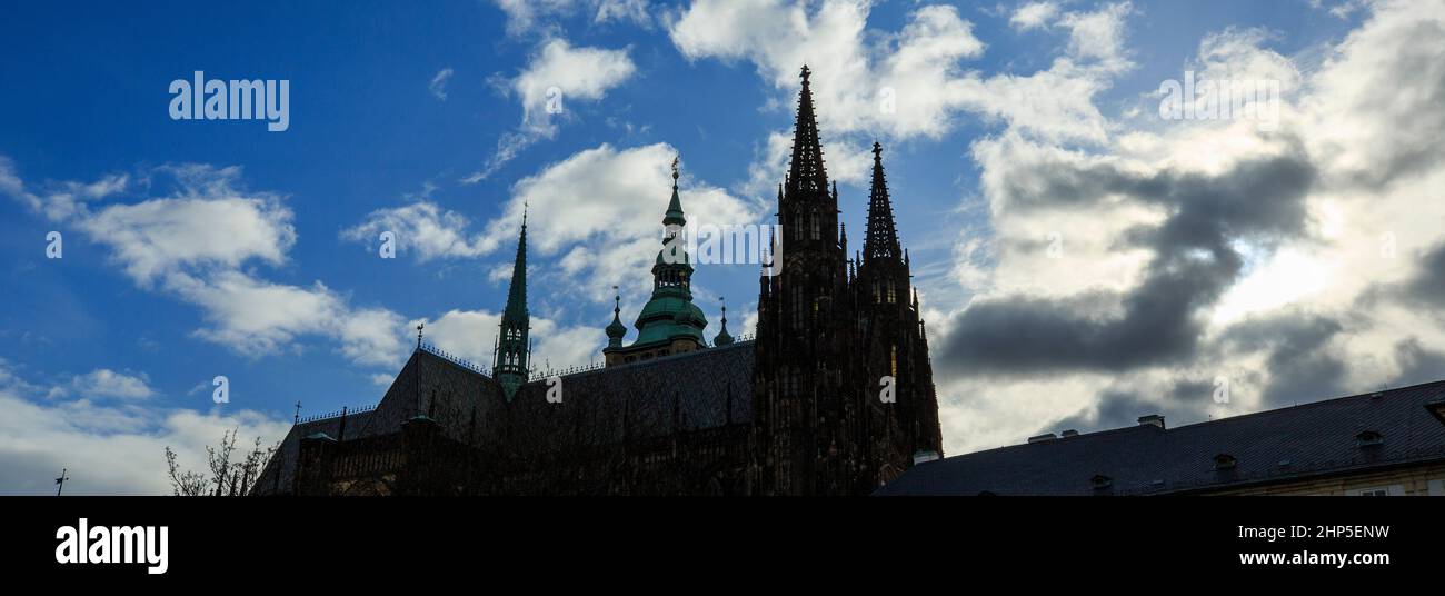 Die Türme und die Kuppel der St.-Veits-Kathedrale in Silhouette vor einem blauen Himmel mit weißen Wolken auf der Prager Burg, Prag, Tschechische Republik Stockfoto