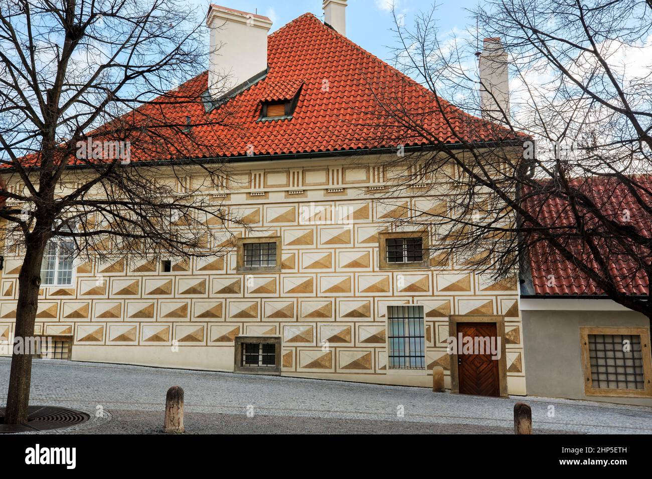 Renaissance-Haus mit Sgraffito-Ziegeln, die eine visuelle Illusion schaffen, mit Quadraten und Dreiecken und Diamanten, rotes Ziegeldach, in der gepflasterten Straße, Prag Stockfoto