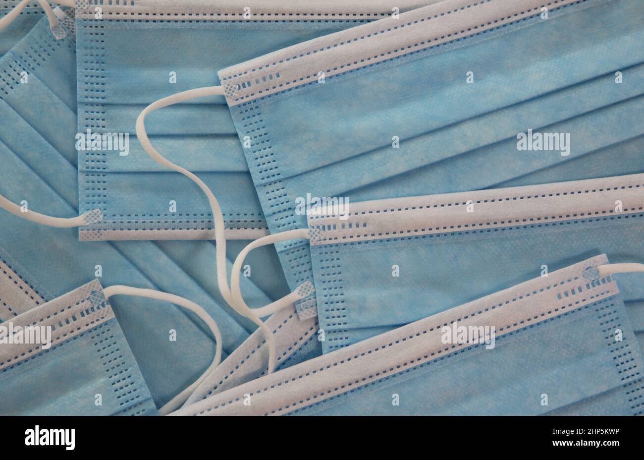 Hintergrund der Nahaufnahme mehrerer, hellblauer und weißer medizinischer Masken, Schutz vor Infektionskrankheiten Stockfoto