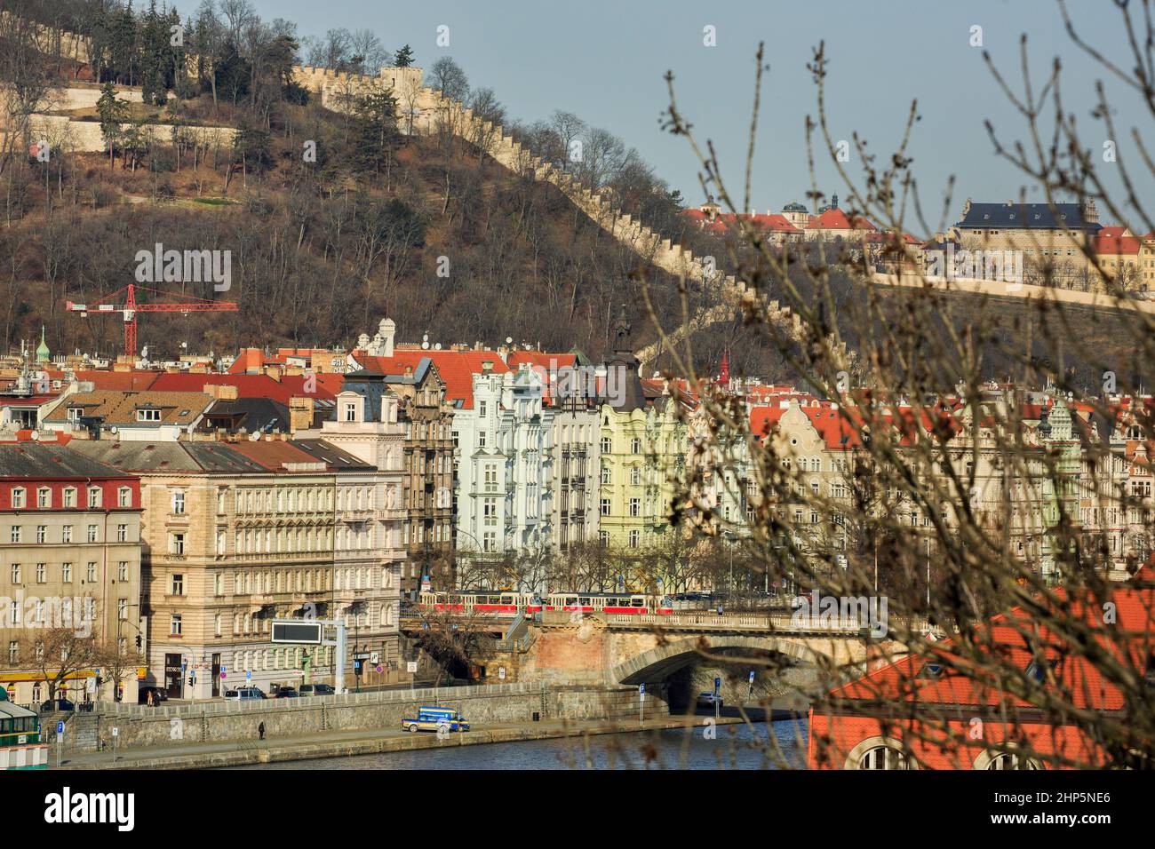 Kastellationen der Burgmauer auf dem Petrin-Hügel, Hradcany, Prag, Tschechische republik, von der Vysehrad-Festung aus gesehen, mit der Moldau und einem roten Zug unten Stockfoto