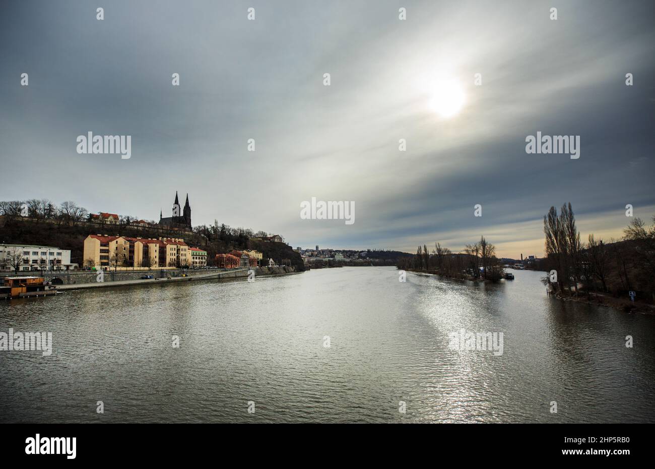 Blick auf die Moldau zur Festung Vysehrad und zur Basilika St. Peter und St. Paul, Prag, Tschechische Republik, ein grauer Tag mit Sonne auf dem Wasser Stockfoto