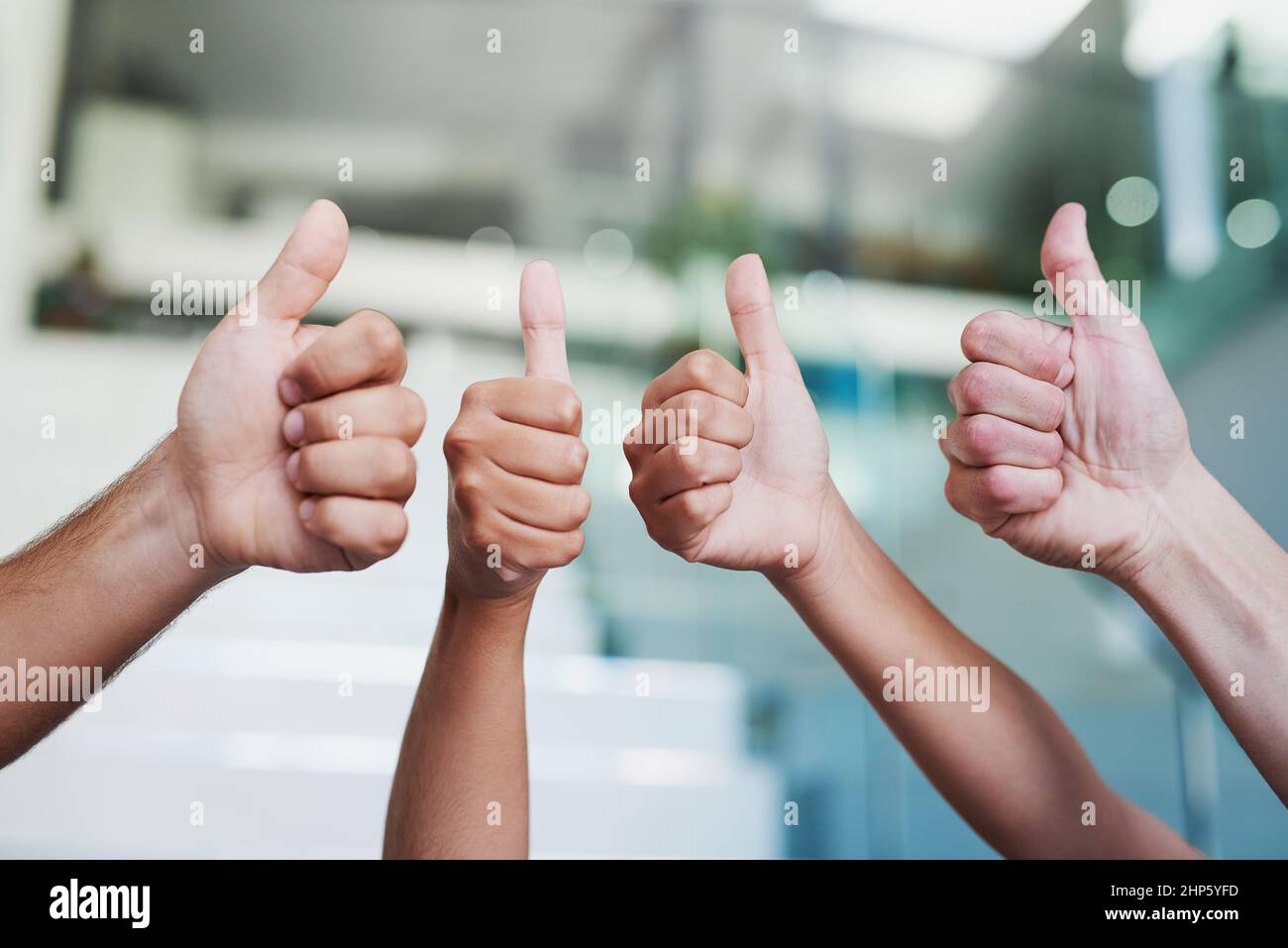 100 genehmigt. Zugeschnittene Aufnahme einer Gruppe von Händen, die in einem Büro Daumen nach oben zeigen. Stockfoto