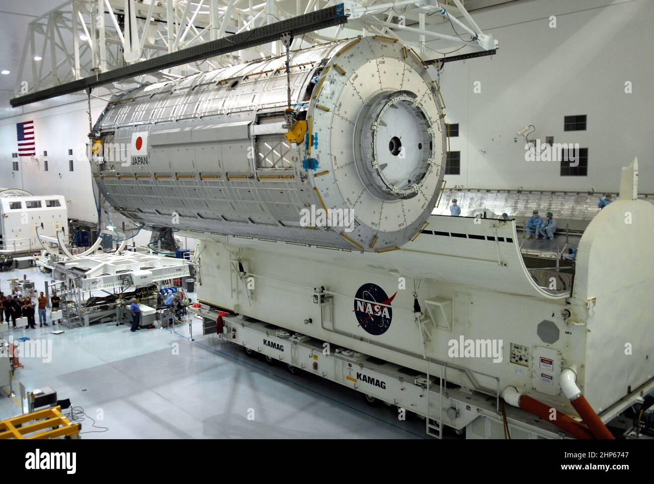 In der Verarbeitungsanlage der Raumstation am Kennedy Space Center der NASA bewegt ein Deckenkran das japanische Experiment-Modul Kibo – Pressurized Module in Richtung des Nutzlastkanisters (unten rechts) ca. 2008 Stockfoto