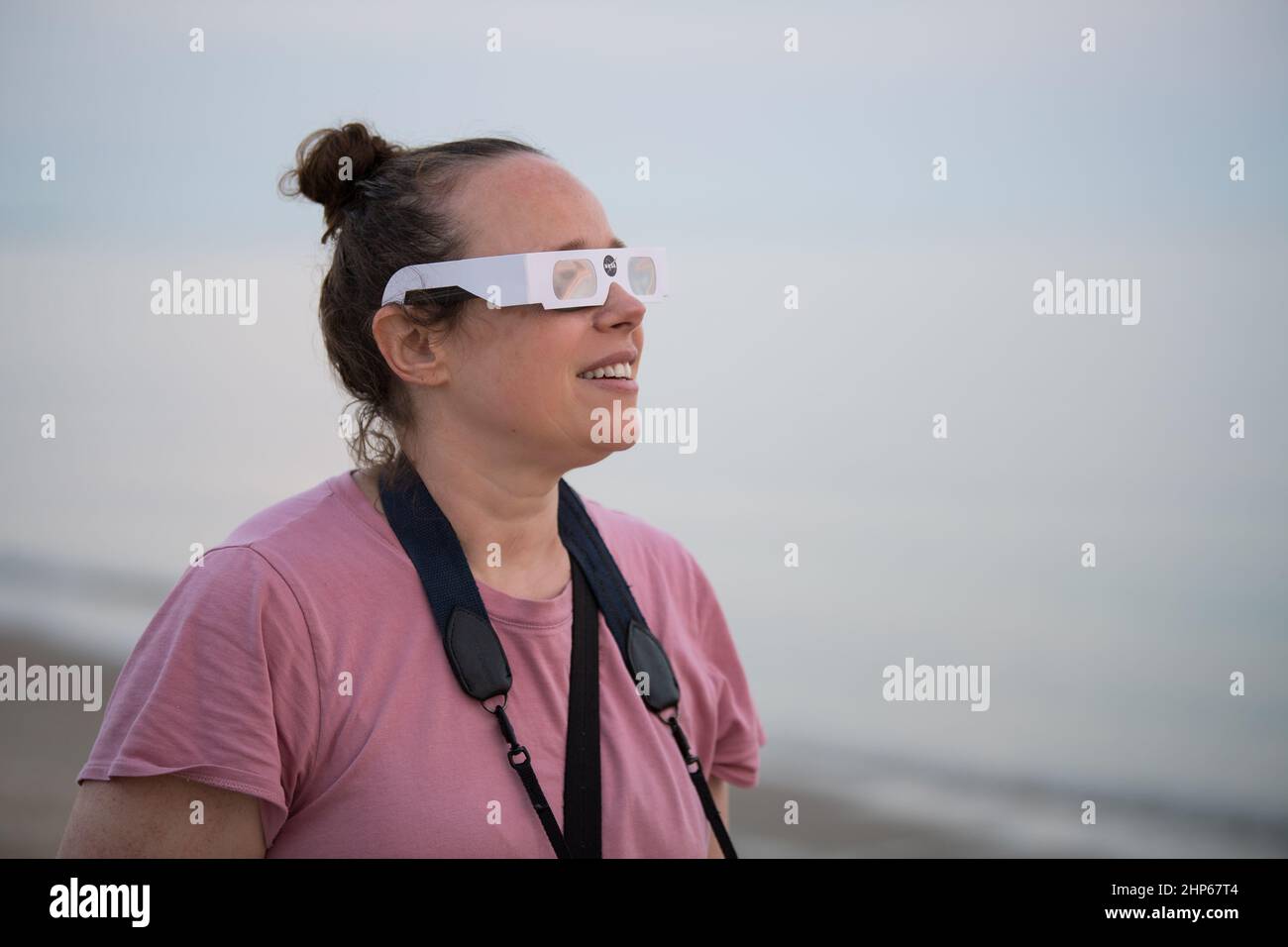 Eine Frau betrachtet die partielle Sonnenfinsternis am Donnerstag, den 10. Juni 2021, am Lewes Beach in Delaware, als die Sonne aufgeht. Die ringförmige oder „Feuerring“-Sonnenfinsternis ist nur in einigen Teilen Grönlands, Nordrusslands und Kanadas sichtbar. Stockfoto