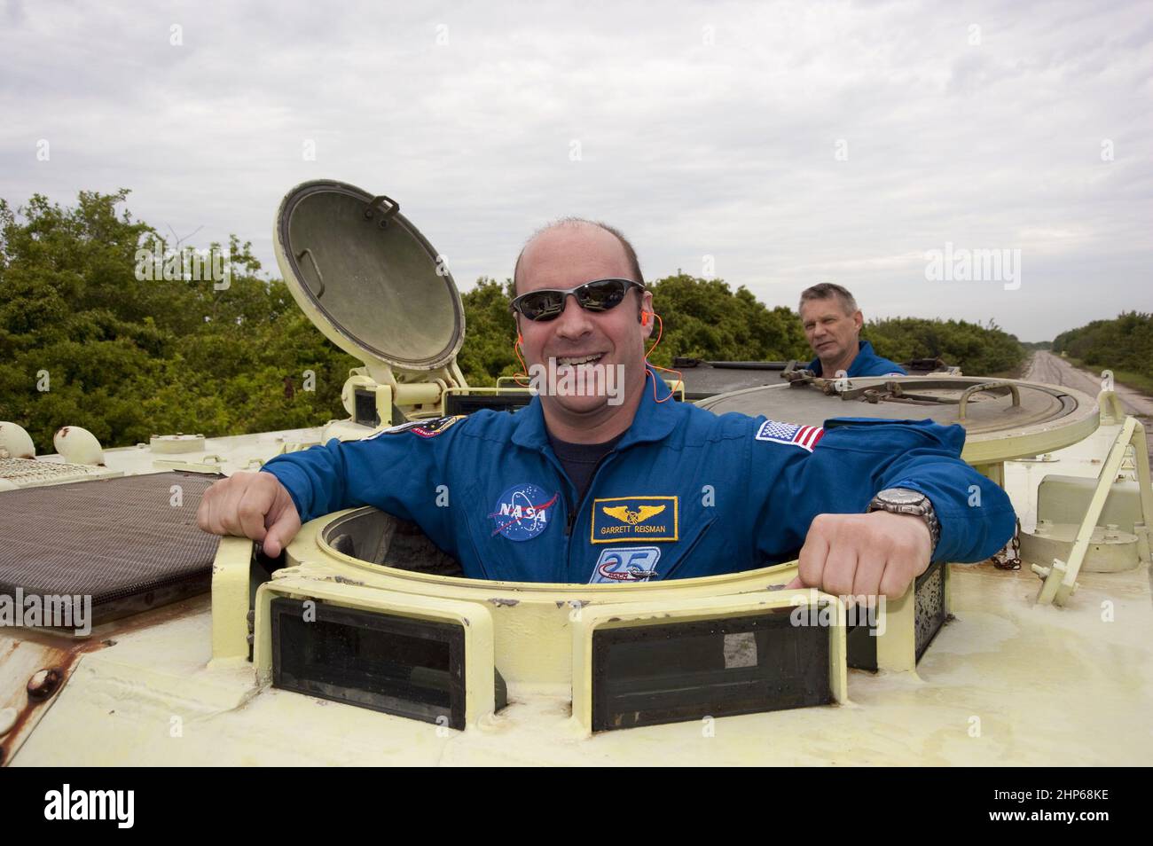 Im Kennedy Space Center der NASA in Florida nimmt sich der STS-132-Missionsspezialist Garrett Reisman eine Auszeit von seinem M-113-Training für gepanzerte Personalleiterträger, um für die Kamera zu posieren, während der Missionsspezialist Piers Sellers auf ca. 2010 Stockfoto