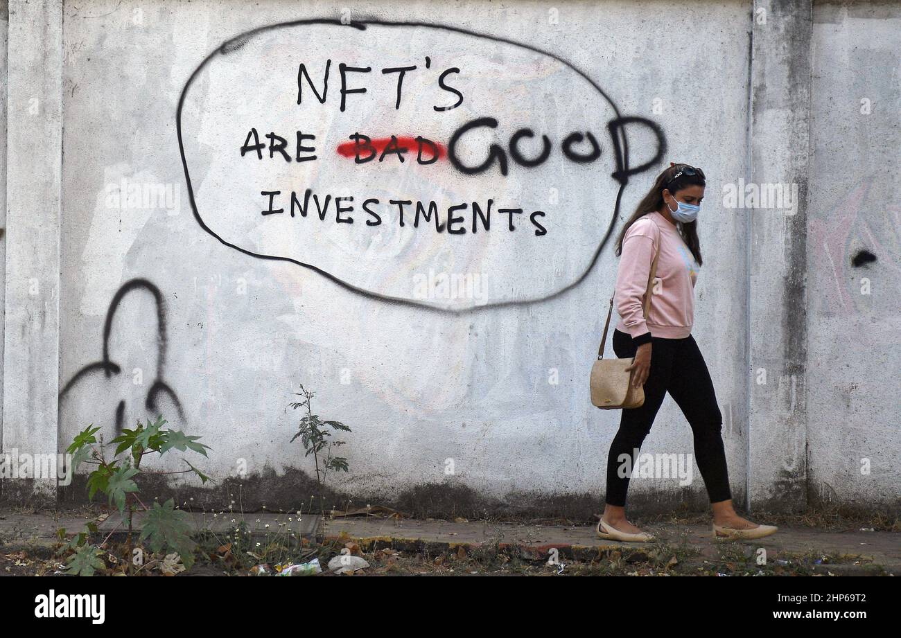 Mumbai, Indien. 18th. Februar 2022. Eine Frau, die eine Schutzmaske trägt, geht an einem Graffiti vorbei, das auf einer Wand mit der Aufschrift "NFT's are Good Investments" in Mumbai gemalt ist.Non fungible Tokens (NFT) sind digitale Vermögenswerte, die reale Objekte wie Kunst, Musik, Fotos usw. repräsentieren. Kredit: SOPA Images Limited/Alamy Live Nachrichten Stockfoto