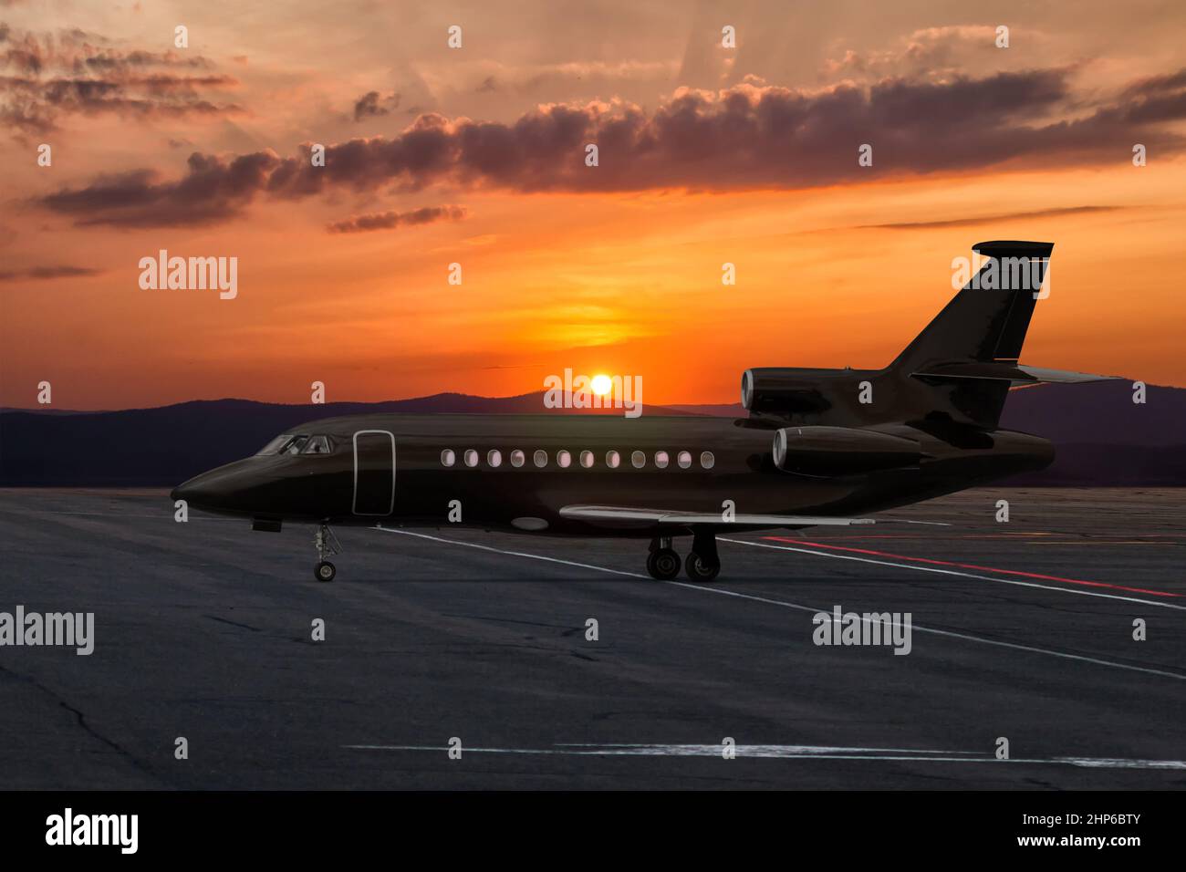 Schwarzer Executive Business Jet am Flughafen vor dem Hintergrund eines malerischen Sonnenuntergangs Stockfoto