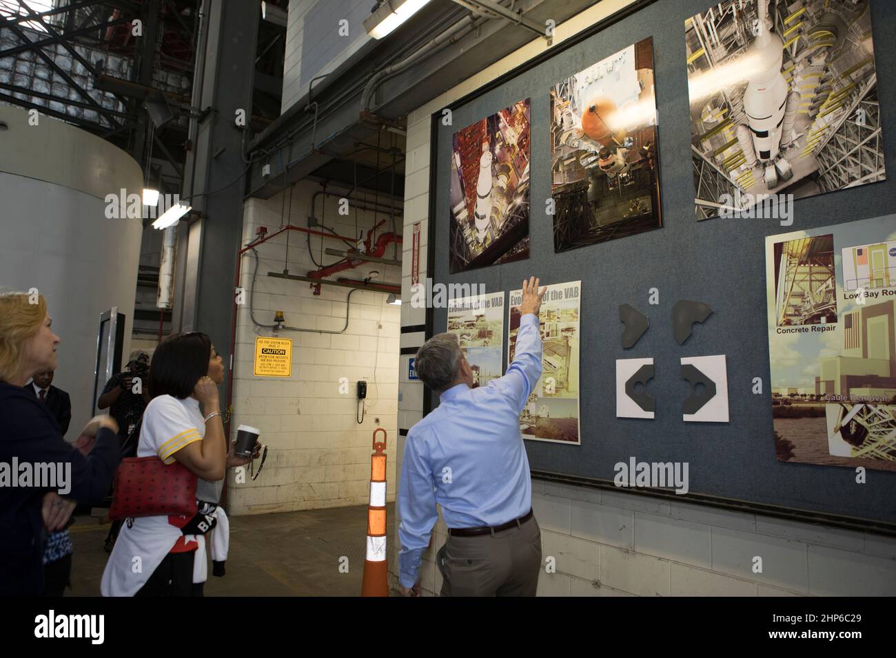 Bob Cabana, Direktor des Kennedy Space Center, zeigt auf eine Ausstellung während einer Tour für die Darsteller und Crew-Mitglieder des kommenden Filmes „Hidden Figures“. Die Gruppe geht zu Fuß, dachte der Transfergang des Fahrzeugmontagehaus ca. 2016 Stockfoto