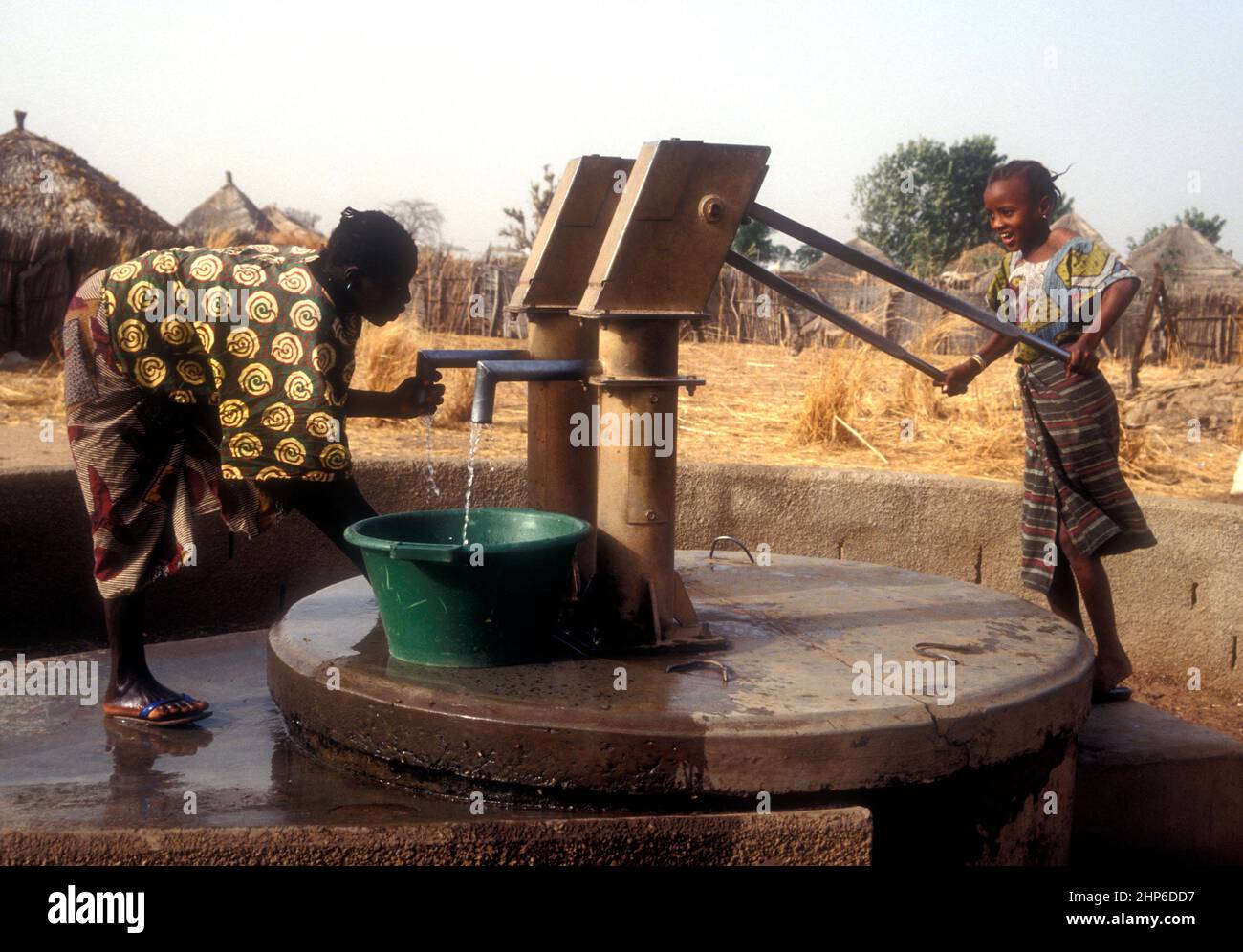 Mädchen pumpt Wasser aus einem sicher bedeckten Brunnen in Gambia, Westafrika Stockfoto
