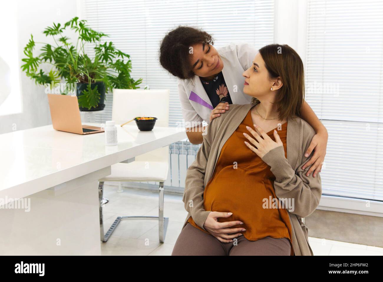 Junge, glückliche, dankbare Patientin umarmt sich mit einer freundlichen, positiv-afroamerikanischen Ärztin, nachdem sie gute Testergebnisse oder eine Genesung während des Tests erhalten hatte Stockfoto