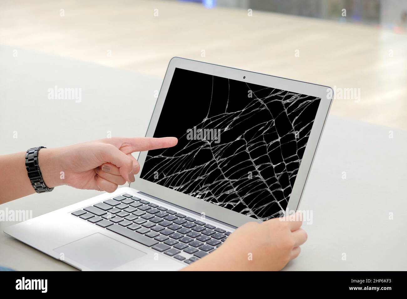 Linke Hände Frauen hat sie zeigen einen tragbaren Computer Laptop Bildschirm auf Riss beschädigt und kann nicht für die Arbeit verwendet werden Stockfoto