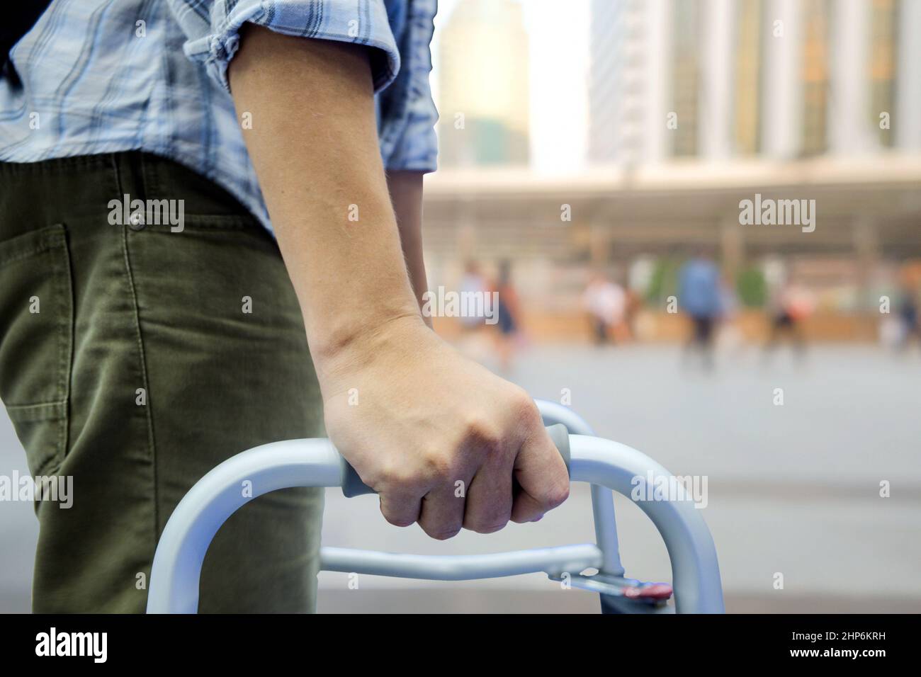 Nahaufnahme und selektiver Fokus der rechten Hand eines Mannes, der ein Gehgerät verwendet hat, um ihn dabei zu unterstützen, auf unscharfem Hintergrund im Freien leicht zu laufen Stockfoto