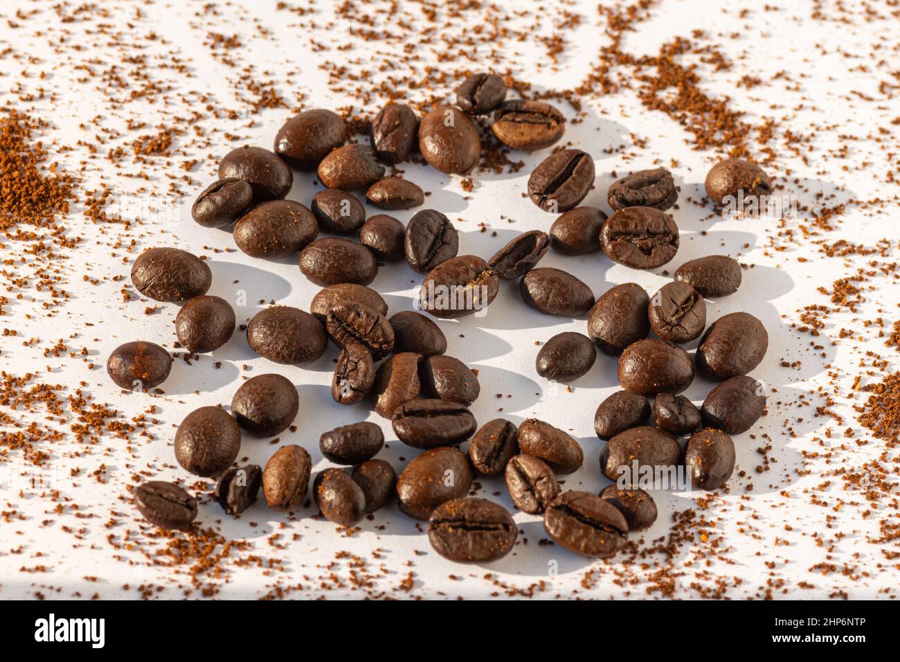 Braun geröstete Kaffeebohnen auf einem Hintergrund von gemahlenem Kaffee auf weißem Hintergrund. Kaffeebohnen für Latte, Cappuccino, Mokka, Americano-Kaffee, macchi Stockfoto