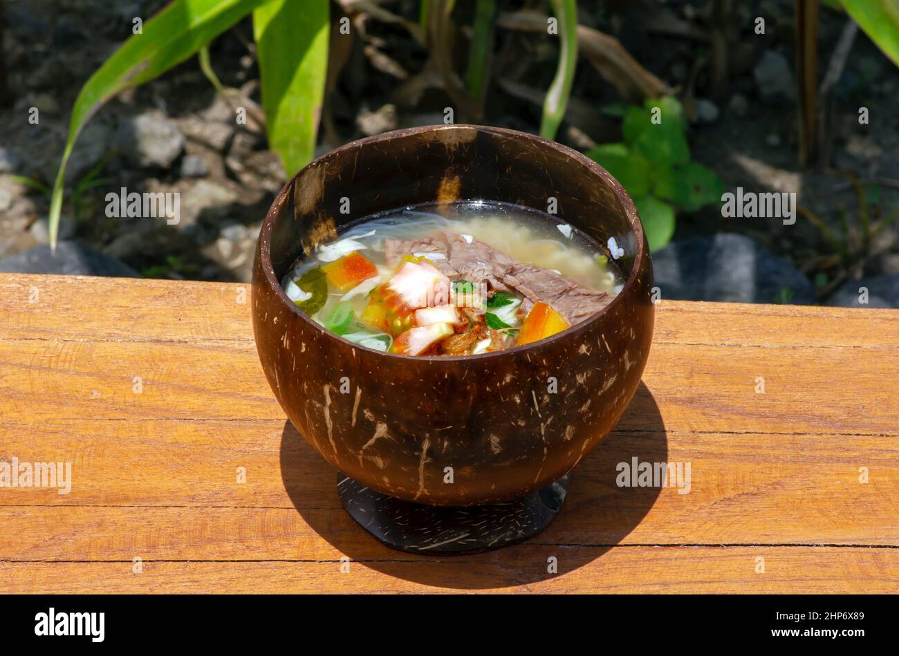 Soto Batok, eine javanesische Rindfleischsuppe mit Gemüse und Reis, serviert in einer traditionellen Schüssel aus Kokosnussschale Stockfoto