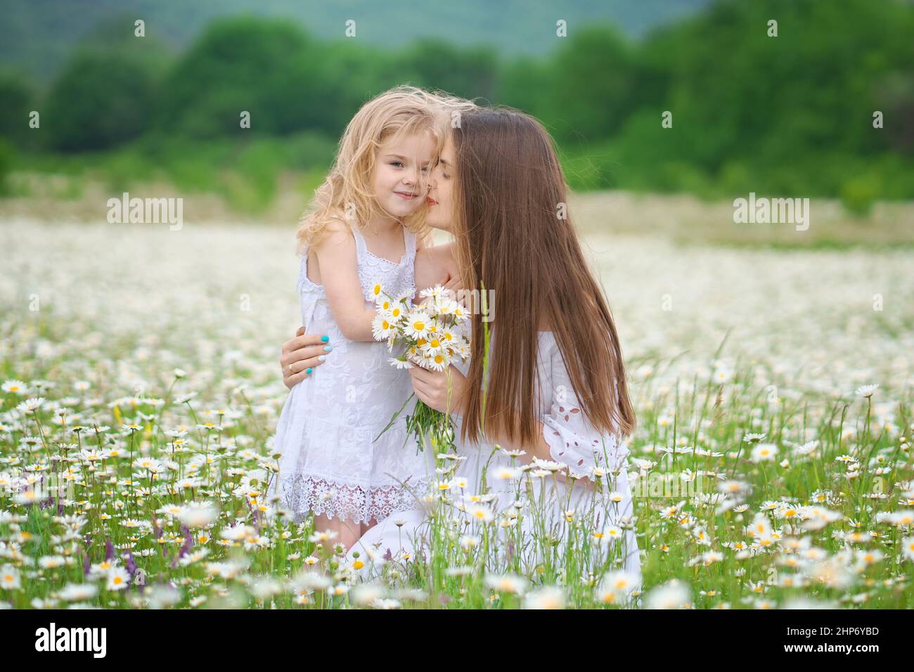 Glückliche Mutter und Tochter in großer Kamillenbergwiese. Emotionale, Liebe und Fürsorge Szene. Stockfoto
