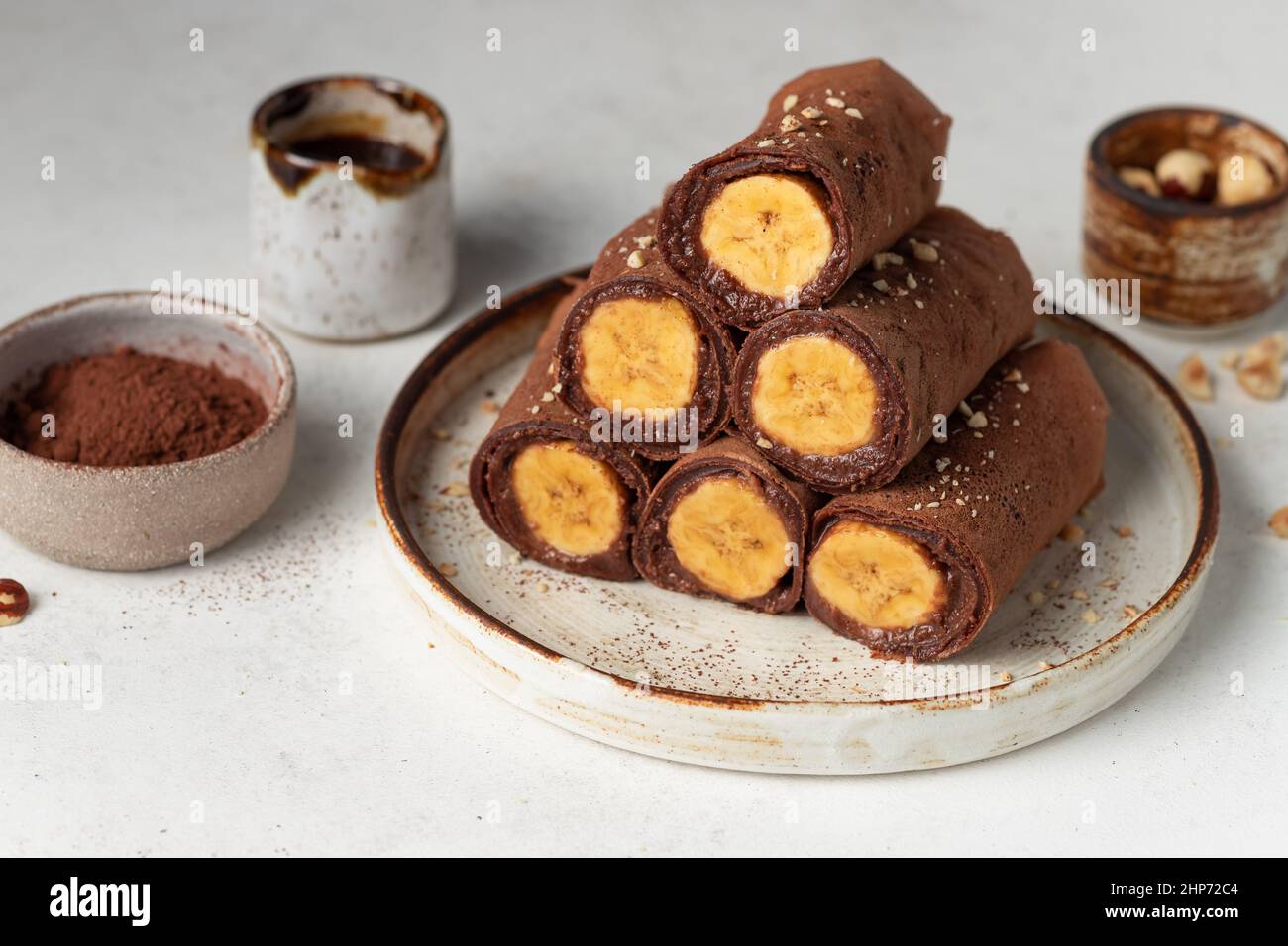 Vegane Schokolade dünne Crepes mit Banane auf Keramikplatte Stockfoto