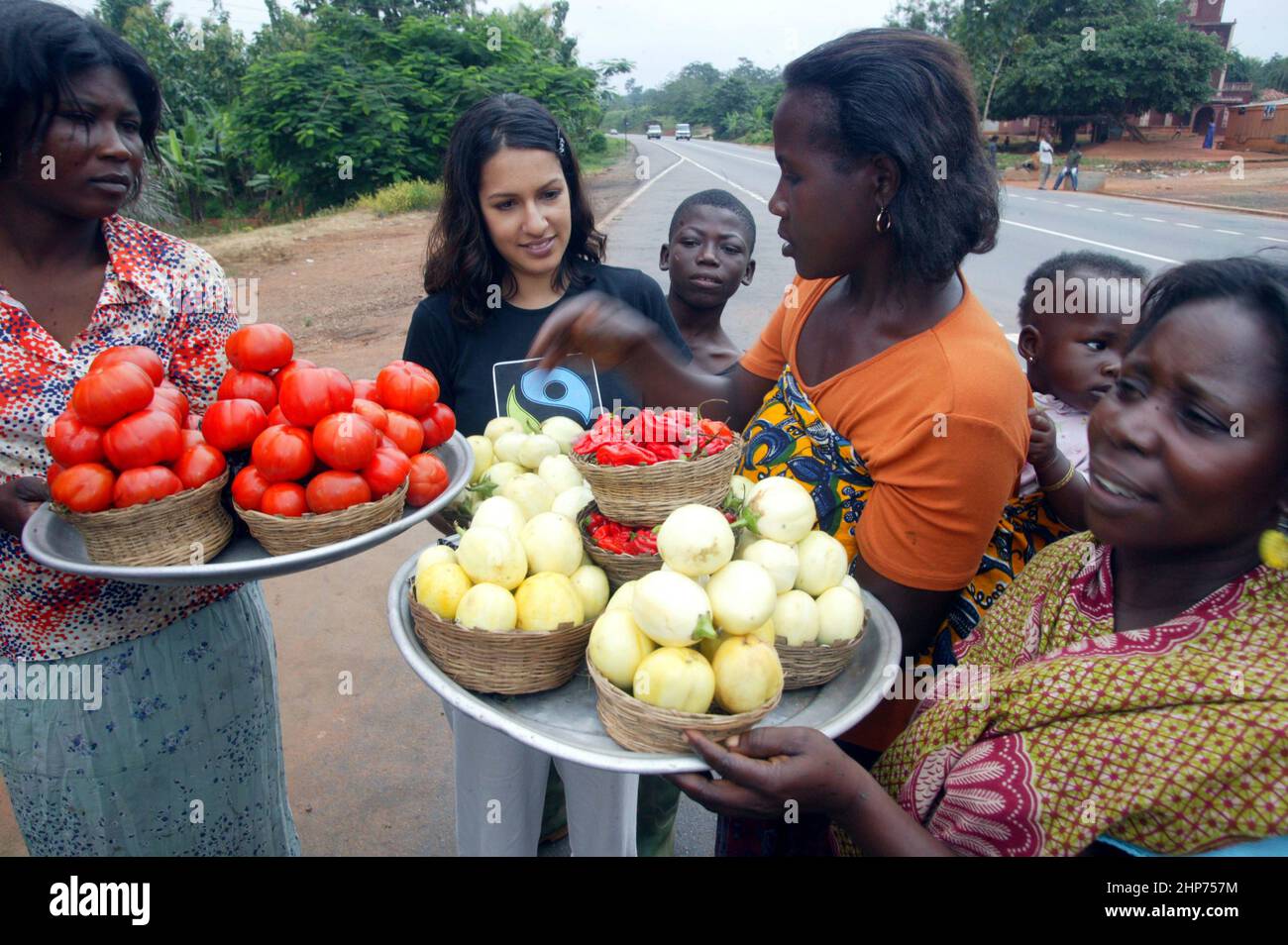 Ghanaische Straßenhändler verkaufen Obst und Gemüse an die berühmte Essensschriftstellerin Vicky Bhogal. Eine Aktivistin von Causes Vickys berühmtes Rezeptbuch für die Make Poverty History Kampagne, „A Fair Feast“ im Jahr 2005, das sie zusammenstellte und herausgab. Das Buch bestand darauf, dass 100% des Erlöses an wohltätige Zwecke gehen, und brachte über £100.000 für die Fairtrade Foundation und Oxfams Make Trade Fair Campaign ein. Bild Gary Roberts/worldwidefeatures.com Stockfoto