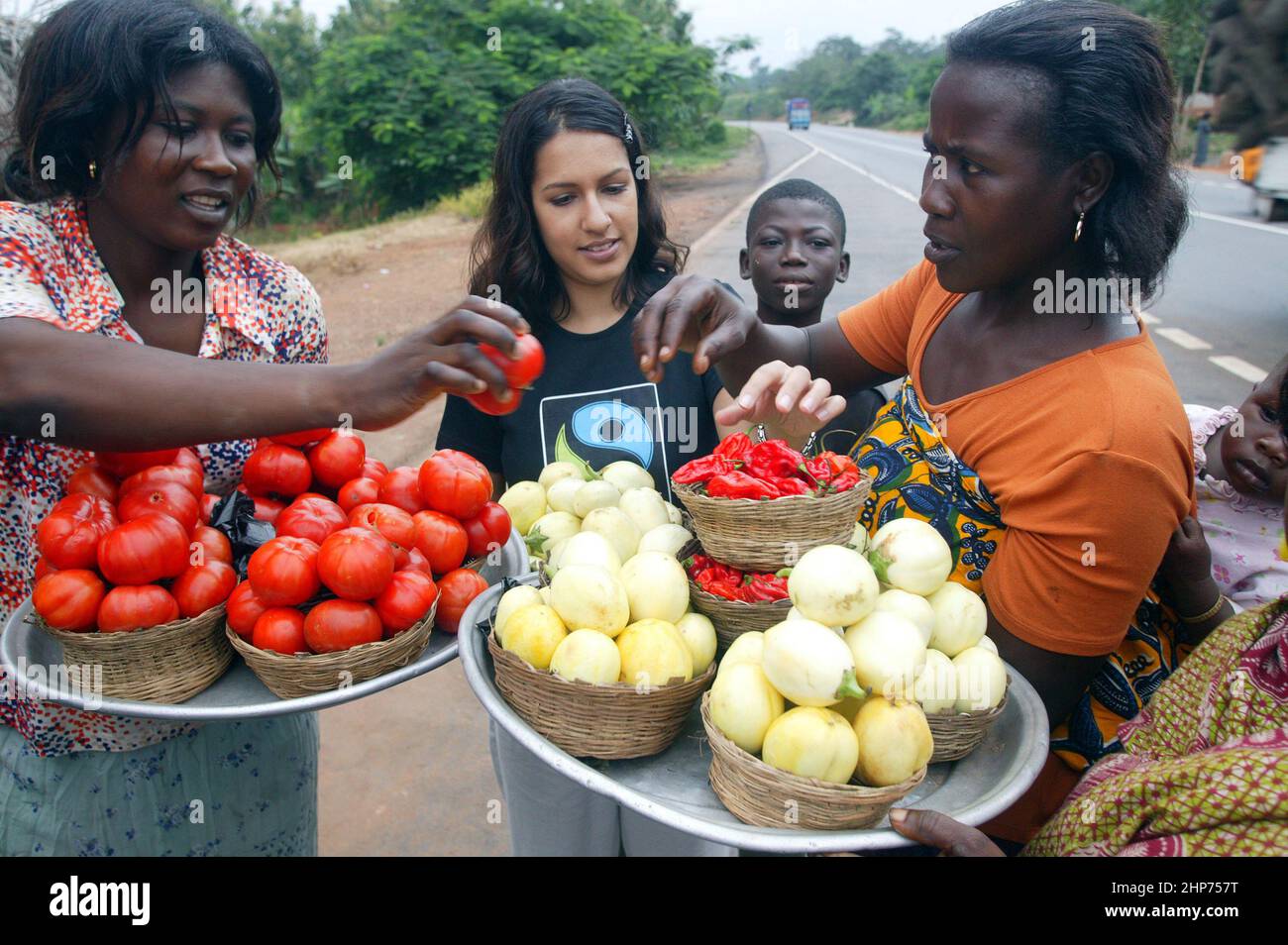 Ghanaische Straßenhändler verkaufen Obst und Gemüse an die berühmte Essensschriftstellerin Vicky Bhogal. Eine Aktivistin von Causes Vickys berühmtes Rezeptbuch für die Make Poverty History Kampagne, „A Fair Feast“ im Jahr 2005, das sie zusammenstellte und herausgab. Das Buch bestand darauf, dass 100% des Erlöses an wohltätige Zwecke gehen, und brachte über £100.000 für die Fairtrade Foundation und Oxfams Make Trade Fair Campaign ein. Bild Gary Roberts/worldwidefeatures.com Stockfoto