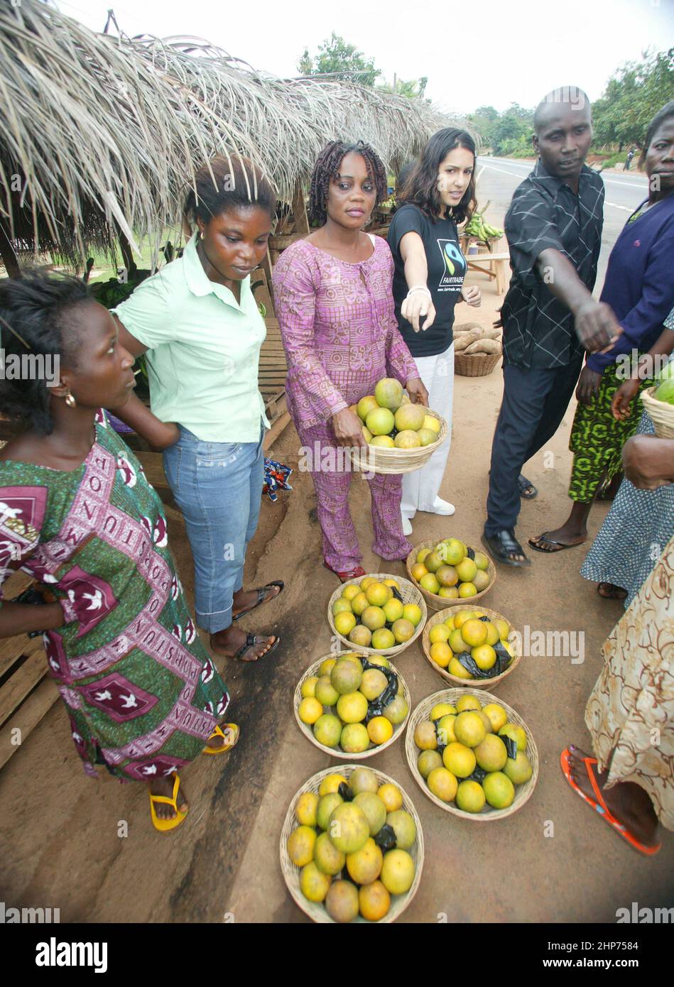 Ghanaische Straßenhändler verkaufen Obst und Gemüse an die berühmte Essensschriftstellerin Vicky Bhogal. Eine Aktivistin von Causes Vickys berühmtes Rezeptbuch für die Make Poverty History Kampagne, „A Fair Feast“ im Jahr 2005, das sie zusammenstellte und herausgab. Das Buch bestand darauf, dass 100% des Erlöses an wohltätige Zwecke gehen, und brachte über £100.000 für die Fairtrade Foundation und Oxfams Make Trade Fair Campaign ein. Bild Gary Roberts/worldwidefeatures.com Stockfoto