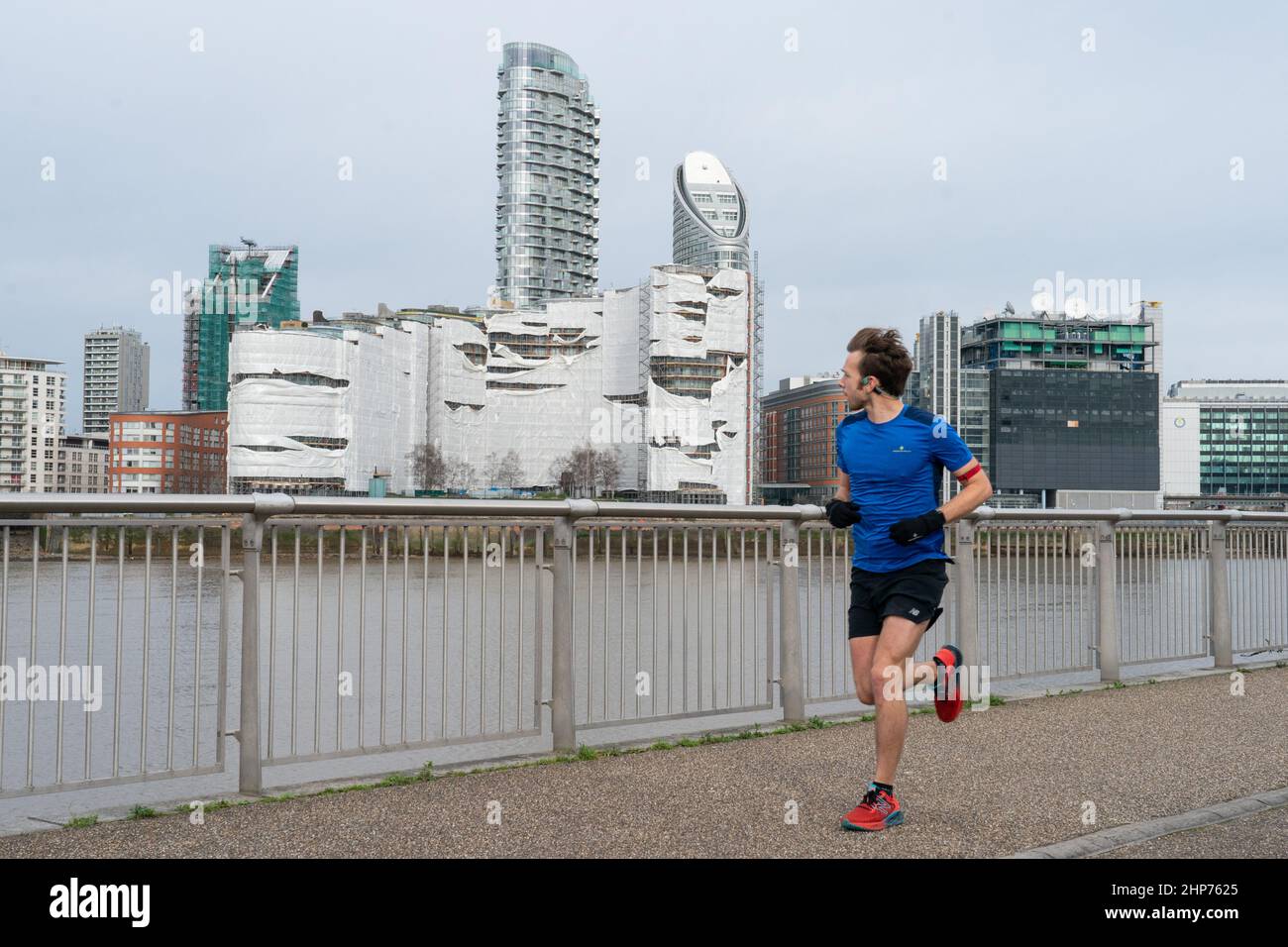 Ein Läufer schaut nach starken Winden, die der Sturm Eunice einschlug, auf eine Baustelle an der Themse in London. Eine große Säuberung wird beginnen, nachdem Sturm Eunice Schäden, Störungen und rekordverdächtige Windböen in Großbritannien und Irland verursacht hat, die zum Tod von mindestens vier Menschen führen. Bilddatum: Samstag, 19. Februar 2022. Stockfoto