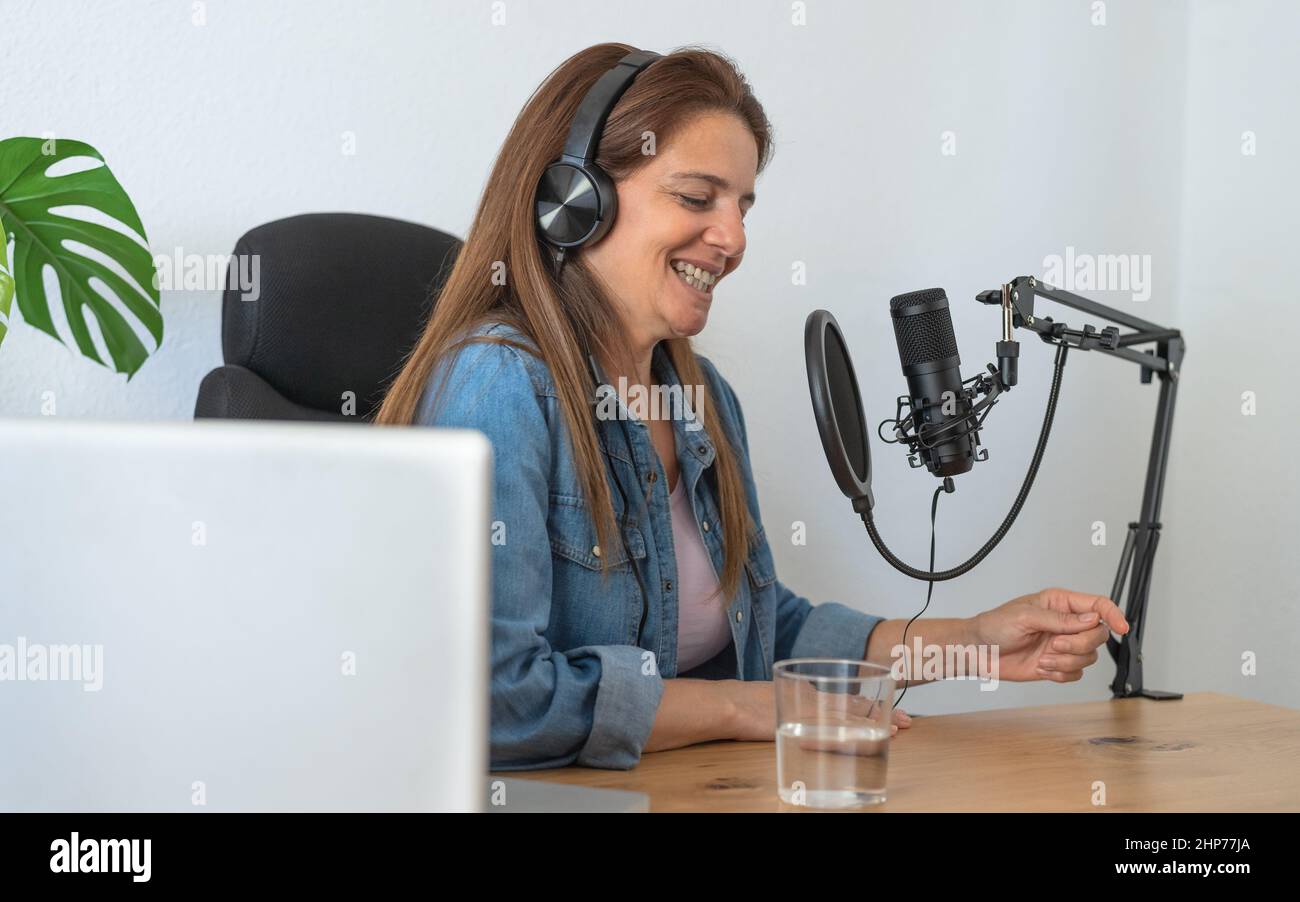 Reife Frau, die aus ihrem Heimstudio einen Podcast mit Mikrofon und Laptop aufnahm Stockfoto