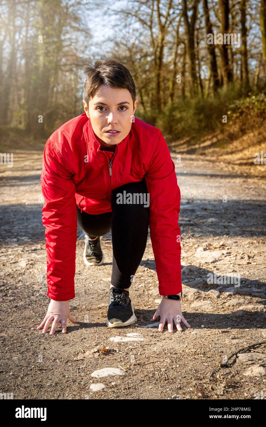 Der Läufer beginnt im Wald zu laufen. Die junge Frau trägt eine rote Jacke und trainiert im Wald. Konzept von Wellness und Natur. Stockfoto