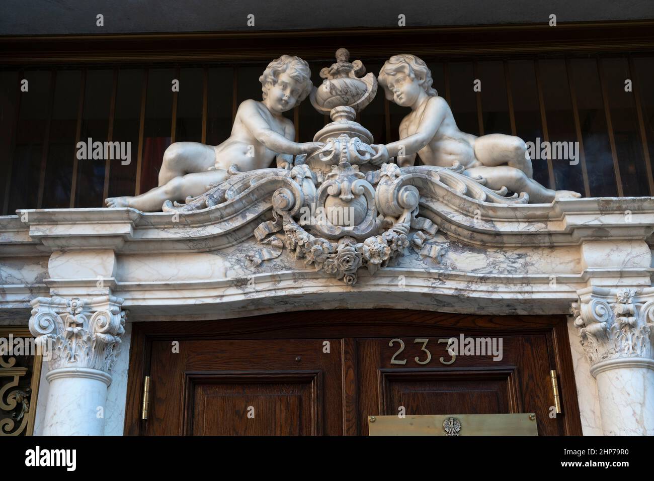 Marmorputti überragt die Eingangstür eines denkmalgekennzeichneten Mansion von Manhattan aus den Jahren 1902 bis 1905. Es beherbergt jetzt das polnische Konsulat für New York City. Stockfoto