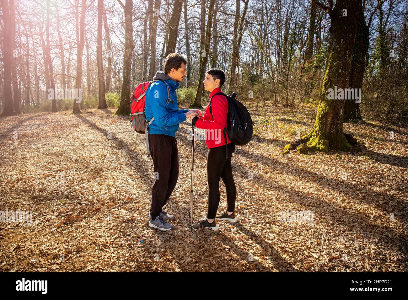 Schönes junges Paar ist Wandern im Wald. Der Mann spricht mit dem Mädchen über sie, als er sie in die Hände nimmt. Reise- und Naturkonzept. Stockfoto