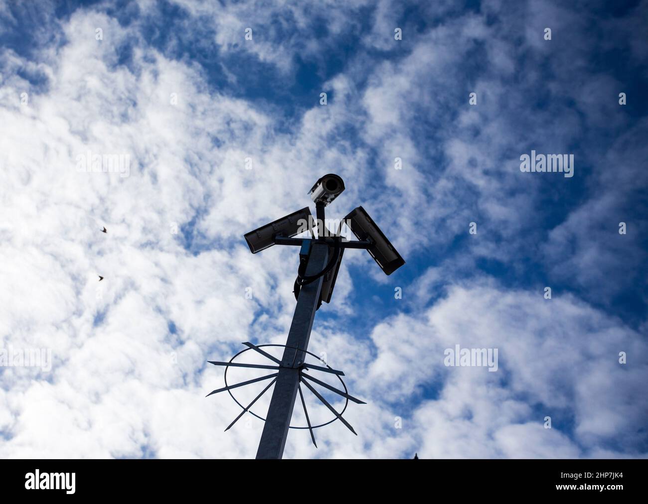 CCTV-Kameras auf einem Laternenpfahl mit Wolken hinter ihnen am Bahnhof Maidstone East, Kent, Großbritannien. Stockfoto
