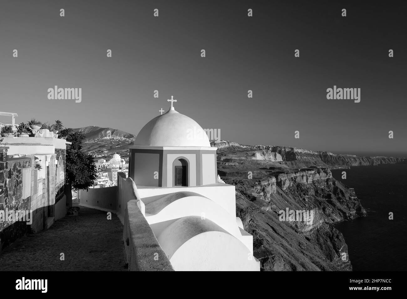 Blick auf eine wunderschöne orthodoxe Kirche, den blauen Himmel und die Ägäis in Santorini Griechenland in Schwarz und Weiß Stockfoto