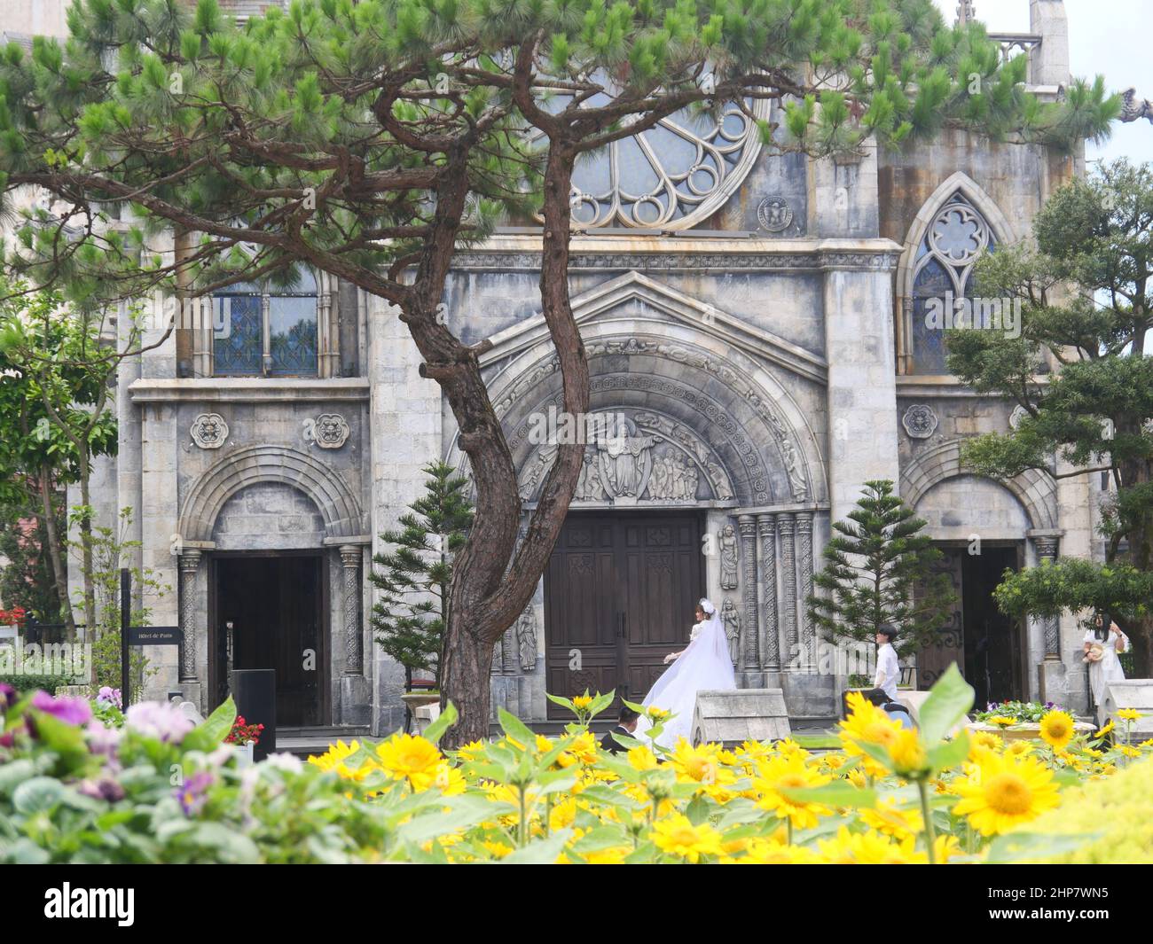 Da Nang, Vietnam - 12. April 2021: Touristen und Paare, die Hochzeitsfotos vor einer Kirche im französischen Dorf in Ba Na Hills machen, ein berühmtes Thema Stockfoto