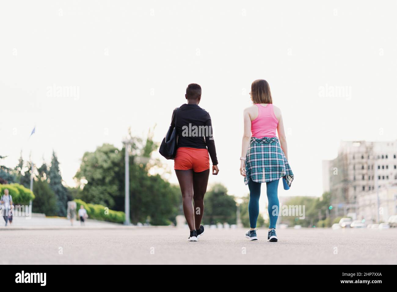 Freunde Rückansicht in Sportswear Wandern nach einer Sportveranstaltung in der Stadt diskutieren. Multiethnische Frauen mit einem Fitness-Workout Joggen. Stockfoto
